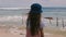 Back view happy little 6-8 year old girl with long hair in hat watching beautiful relaxing scenery at exotic ocean beach