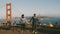 Back view happy man and woman walk together holding hands at epic beautiful view of Golden Gate Bridge in San Francisco.