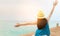 Back view of happy young Asian woman in casual style fashion and straw hat relax and enjoy holiday at tropical paradise beach.