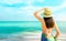 Back view of happy young Asian woman with straw hat relax and enjoy holiday at tropical paradise beach. Girl in summer vacation