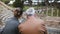 Back view of happy young European girl sitting together with older man talking at ruins of Ostia amphitheater in Italy.