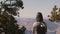 Back view happy young traveler woman hiking, taking smartphone photo of amazing Grand Canyon view scenery touching hair.