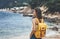 Back view hipster girl with backpack in sand coastline on nature landscape, mock up. Traveler on background beach seascape