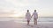 Back view of hispanic just married senior couple walking on beach at sunset