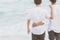 Back view homosexual portrait young asian couple standing hug and look together on beach in summer