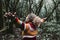 Back view of joyful woman with arms up standing in the deep forest. Nature environment activist people. Love for forest and