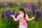 Back view. kid girl in a T-shirt and shorts walks on a lupine field alone