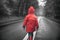 Back view of little boy in red raincoat walking on the street alone