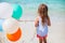 Back view of little girl with balloons at beach