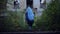 Back view of little girl with blue hair, wearing halloween costume of unicorn, with sweets bucket, walking to scary house.