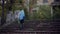 Back view of little girl with blue hair, wearing halloween costume of unicorn, with sweets bucket, walking up stairs to scary aban