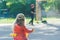 Back view of little girl looking at playing boy on kids street football ground