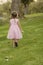 Back view of little girl in pink dress on grass