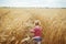 BACK VIEW: A little girl walks on a yellow agricultural field