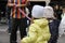 Back view of little girl on winter day in the street. On the background a street vendor is making balloon figures. Happy children