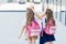 back view of little schoolgirls making horns gesture to each other