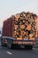 Back view of loaded European truck with sawed cutted woods in motion on asphalt road, transportation and delivery concept. Detail