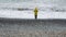 Back view of lone woman in yellow coat on seashore. Depression, mood, sadness