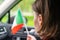 Back view of lonely girl with flag of Italy near rainy window with drop in a car.