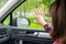 Back view of lonely girl touching by hand rainy window with drop of car.