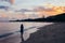 Back view of lonely woman walking on beach in sunset