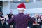 Back view of a male conductor, wearing casual outfit with red santa hat, conducting his young band performing Christmas music at