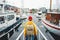 Back view of male tourist with traveling backpack wearing yellow raincoat standing on pier