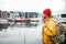 Back view of male tourist with traveling rucksack standing among fishing boat on city pier