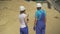 Back view of male worker and female inspector standing in front of stack of yellow sand and talking. Caucasian man