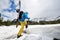 Back view of man carrying snowboard on his back on challenging snowy route for off-piste snowboarding riding. Copy space