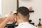 Back view of man getting short hair trimming at barber shop with clipper machine