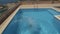 Back view of man in red swim shorts running and jumping to the swimming pool.