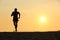 Back view of a man running on the beach at sunset