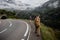 back view of man with smartphone photographing young woman walking on road near mountain tunnel