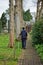 The back view of a man walking up a path that has large trees either side of it