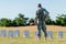 Back view of military man holding american flag near headstones