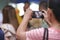 Back view of mobile smart phone is held against hands of senior Asian woman in luxury room background. Selective focus and shallow