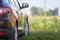 Back view of modern new shiny empty black car parked outside road in grassy looming field on bright summer sunny day on blurred g