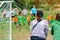 Back view of Moms watch and cheering their sons playing football in school tournament on sideline. Sport, outdoor active,