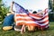 back view of multiracial friends with american flag sitting on green grass