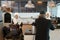 Back view of muslim customer businessman wearing black suit drinking coffee at counter with young muslim barista girls background