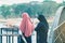Back view of Muslim women relax and admire the beautiful scenery in the evening on The Bridge of the River Kwai in Kanchanaburi,