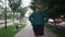 Back view obese woman walking away in slow motion along city sidewalk. Confident carefree Caucasian overweight plus-size