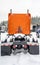 Back view of orange big rig semi truck with Fifth wheel standing on covered with snow winter parking lot