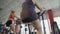 Back view of overweight woman pedalling on stationary bike in the sports club