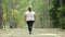 Back view of overweight woman walking at park