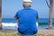 Back view of pensive senior man at beach looking away. Retired enjoying summer holiday at sea