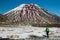 Back view of the person- traveler hiking and tramping with backpack in New Zealand`s mountains, walking toward huge volcano