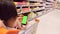 Back view photo of a brunette girl sitting in the shopping cart with the smartphone green screen and someone pushing the