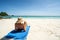 Back view photo of carefree happy female tourist realxing on the sandy beach, sunbating, enjoying summer tropical vacation